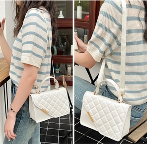Detailed view of white quilted crossbody bag with gold hardware shown on a model