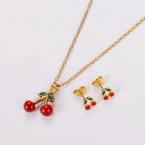 Close-up of golden stainless steel jewelry set with red cherry pendants and earrings