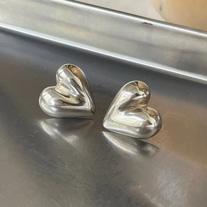 Top view of polished 925 sterling silver heart-shaped stud earrings on metal background