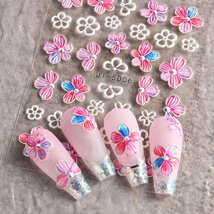 Macro detail of 5D floral nail art stickers with pink camellia and blue flowers