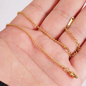 Detailed view of a golden stainless steel ball chain with lobster clasp held in hand