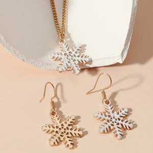 Macro detail of gold-plated snowflake jewelry set with white enamel inlay