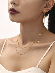 Detail of 18K gold plated floral necklace and fringe earrings set worn by a model