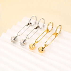 Detail of silver and gold safety pin earrings with polished beads on wave display