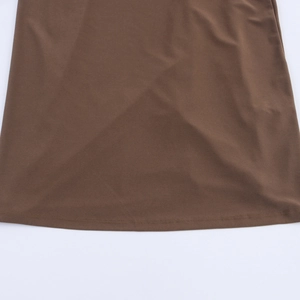 Detailed close-up of brown dress hem showing fine textile texture and quality stitching