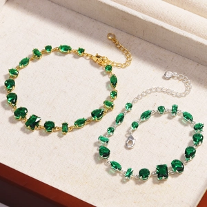 Fashionable green zircon bracelets in gold and silver finish on a textured jewelry tray