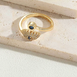 Detailed close-up of golden evil eye ring with blue stones and white zircon on stone base
