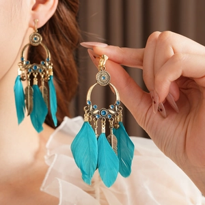 Gros plan sur des boucles d'oreilles bohèmes en bronze avec plumes bleu sarcelle