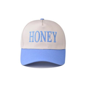 Macro detail of the blue HONEY 3D embroidery on a cream and light blue cotton baseball cap