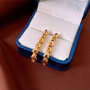 Close-up of vintage golden drop earrings with linked metal chain in navy velvet jewelry box