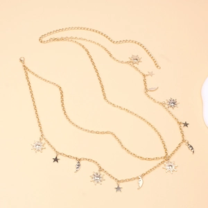 Golden multi-layer body chain with sun moon and star charms on beige background