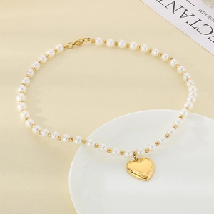 Elegant gold heart pendant necklace with white pearls and OT toggle clasp on ceramic plate