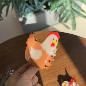 Gros plan d'une pince à cheveux en acétate en forme de poule avec des détails colorés