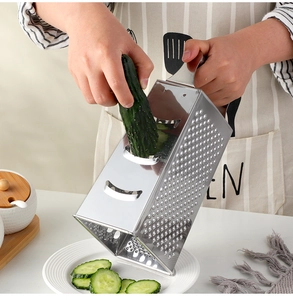 Action shot of a stainless steel 4-sided grater slicing a cucumber into a plate