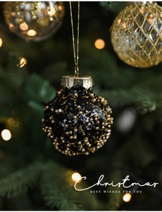 Detail of black Christmas ball with gold beads and snowflake pattern hanger