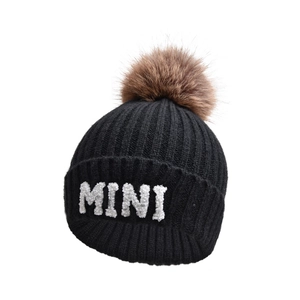 Dettaglio del berretto in maglia nera con ricamo MINI e pompon di pelliccia sintetica