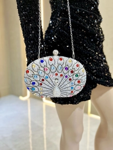 Detailed view of silver peacock evening clutch with colorful rhinestones on a model