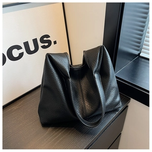 Close-up of black leather tote bag featuring a premium lychee texture finish