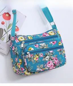 Close-up of the multi-zipper compartments and floral print on the canvas shoulder bag