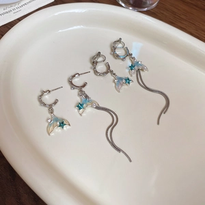 Detail of fishtail earrings with blue gradient pendants and long tassel chains on a tray