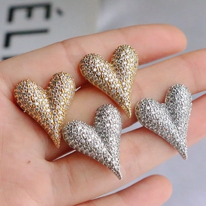 Detailed view of heart-shaped pavé stud earrings in gold and silver finish with white crystals