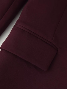Gros plan sur la couture du poignet et la texture du tissu d'une veste bordeaux