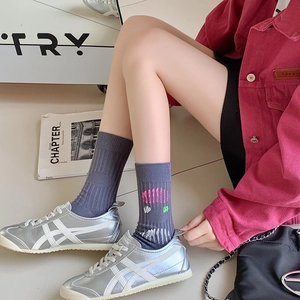 Close-up of ribbed dark grey cotton socks with colorful geometric print and sneakers
