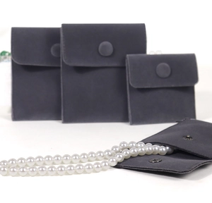 Macro detail of three grey velvet jewelry pouches with snap buttons in various sizes