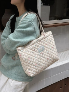 Detail of floral quilted cotton shoulder bag with blue label and soft padding texture