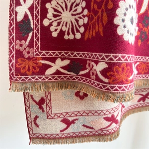 Detail of floral pattern and fringe tassels on red cashmere-like winter scarf