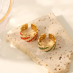 Macro detail of wide 18K gold plated rings with red, green and white enamel patterns