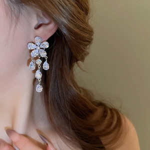 Detail shot of elegant silver flower earrings with zircon tassels on model