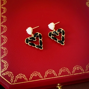 Detail of vintage heart earrings with woven leather chains and pearl cluster accents
