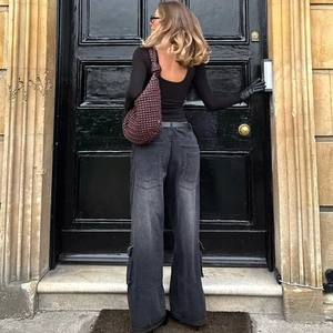 Vista posteriore di jeans cargo grigi vintage abbinati a una borsa in pelle intrecciata