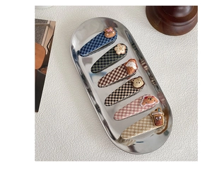 Close-up of six Korean style plaid fabric hair clips with cute 3D charms on a silver tray