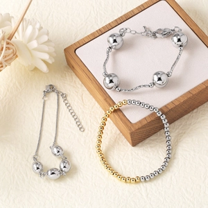 Three elegant round bead bracelets in 18k gold and silver plating on a wooden stand