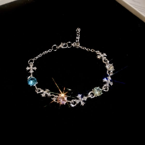 Macro detail of silver cross bracelet with colorful gems on black velvet background