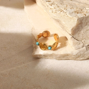 Detail of adjustable gold ring featuring round turquoise stones on natural stone base
