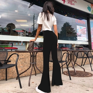 Outdoor back view of women's black high waisted flared trousers with elegant drape
