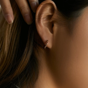 Detail of 18K gold hoop earring with colorful zircons worn by a model in a close-up