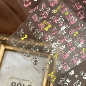 Detail of glitter cherry nail stickers with artistic lettering on a textured background