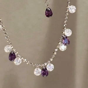Close-up of sparkling purple teardrop and round zircon crystals on silver tassel bracelet