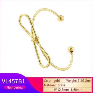 Polished gold brass twist bow cuff bracelet featuring geometric knot and end beads