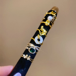 Detailed set of 18K gold-plated rings with zircon, emerald stones, and pearls on black velvet