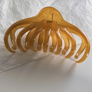 Close-up of translucent amber resin shark hair clip with a large multi-claw design