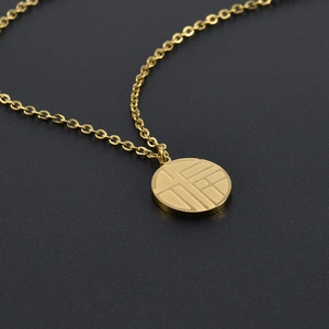 Macro shot of a golden stainless steel Fu character round pendant on a fine O-chain
