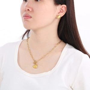 Detail view of model wearing 18K gold heart necklace with OT toggle clasp and matching studs