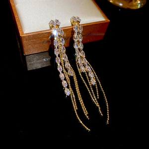 Macro detail of long gold chain tassel earrings with sparkling white zirconia stones
