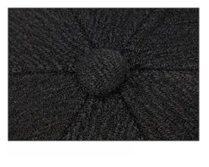 Macro shot of precise stitching and fabric covered top button on a black knit winter cap