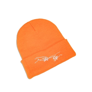 Vue détaillée du bonnet orange vif orné d'une broderie blanche représentant des mains
